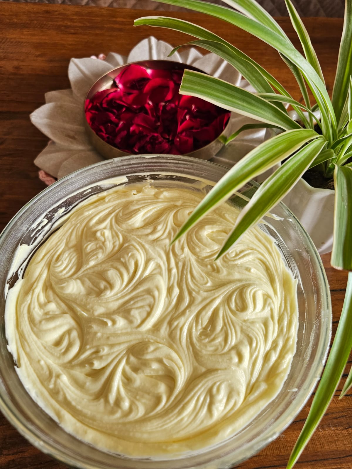 A batch of cream, freshly whipped, beside a bowl of rose petals in Jigisha's kitchen