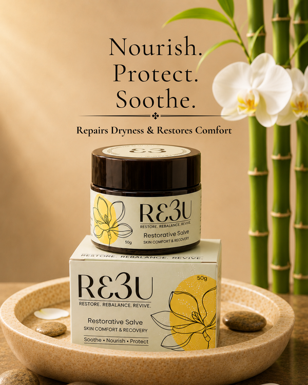 RE3U Restorative Salve jar and box displayed on a wooden tray with spa stones, white orchids, and bamboo stalks against a warm beige background. Text above reads: 'Nourish.