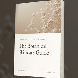 A book titled 'The Botanical Skincare Guide' shown upright against a dark gray background. The cover features a warm beige upper section with delicate white botanical illustrations and a large white lower section with black text.